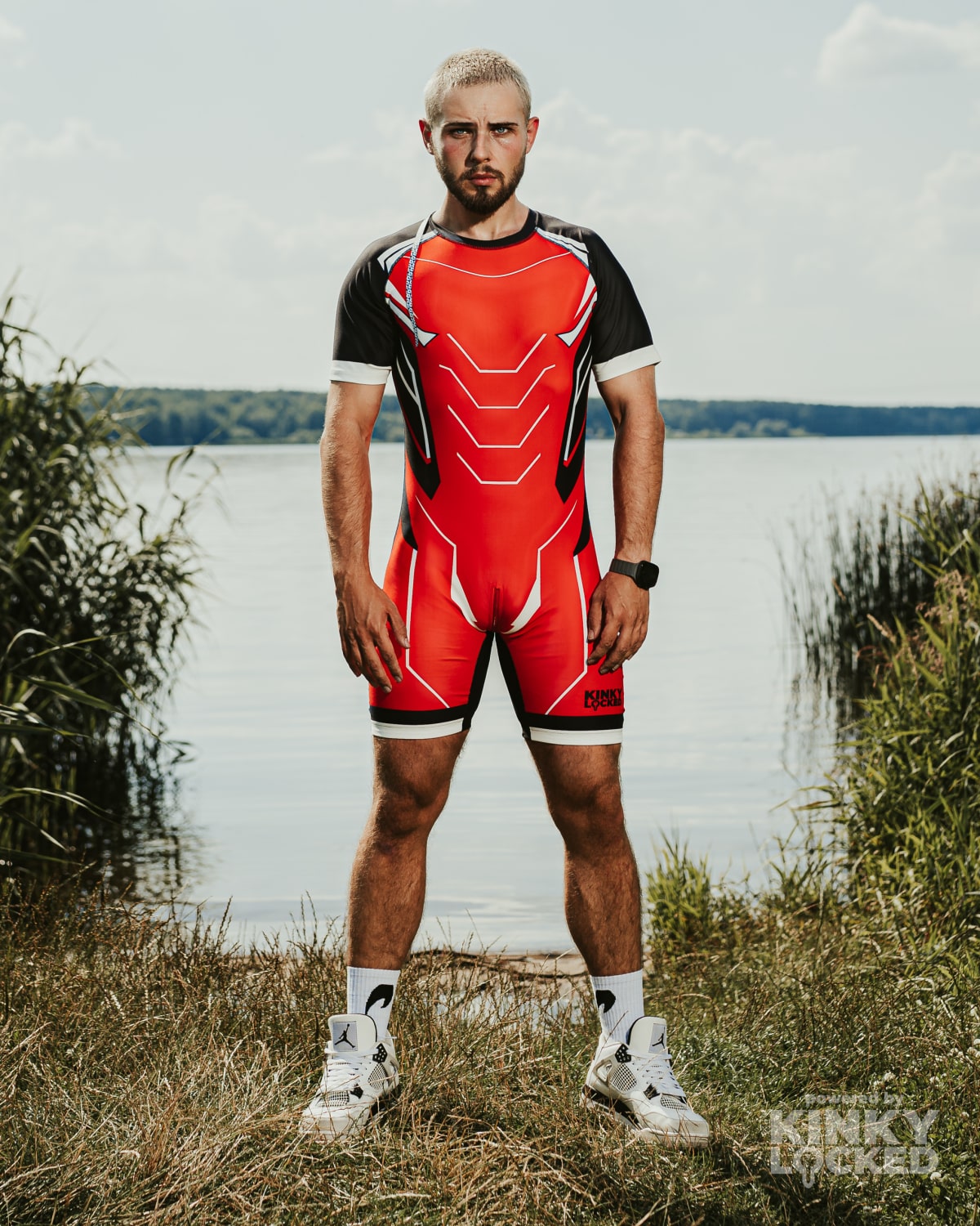 Front view of KINKY LOCKED Bold Red Surfsuit by the water