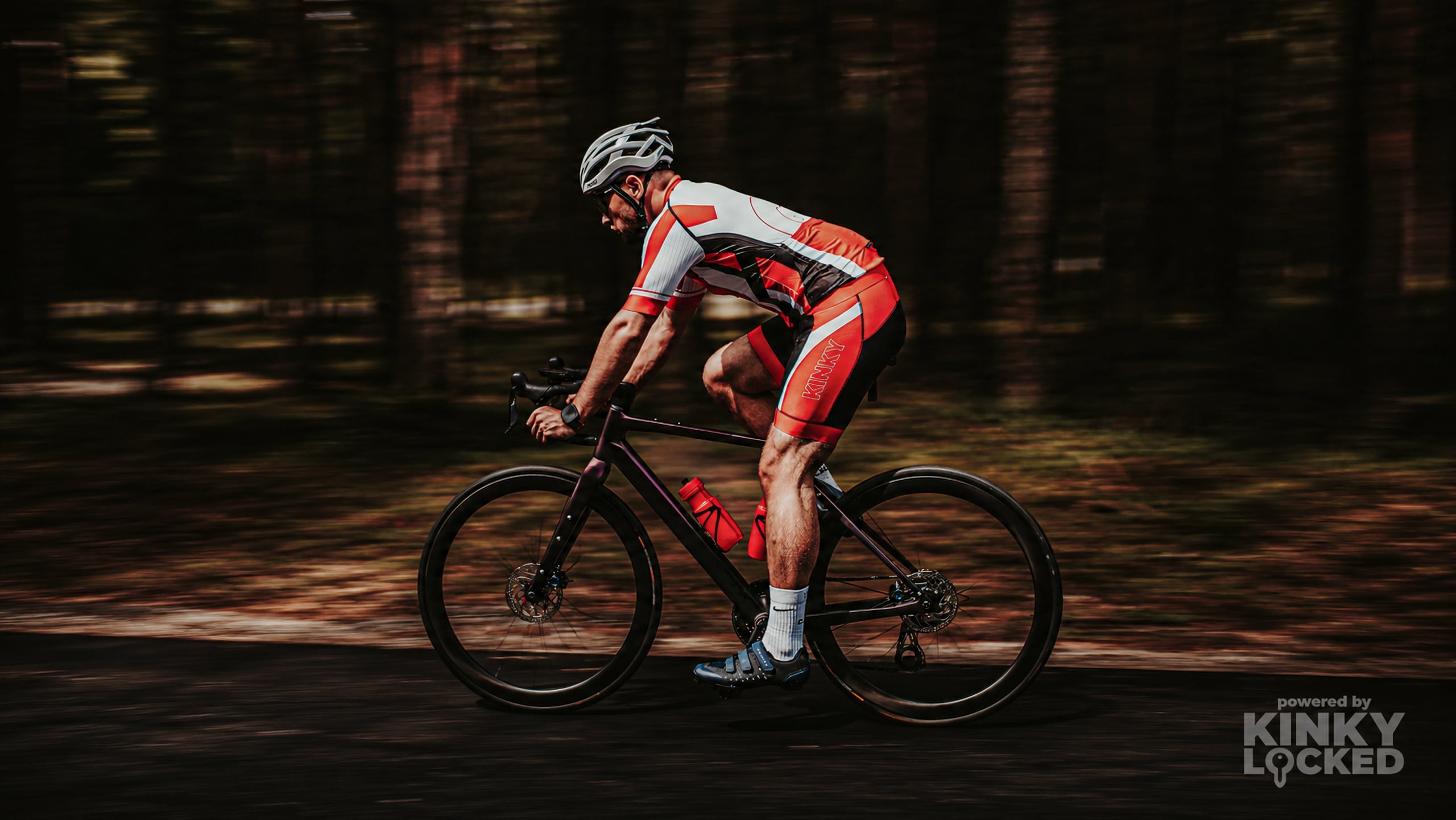 KINKY LOCKED neon red, white and black cycling set worn on a bicycle
